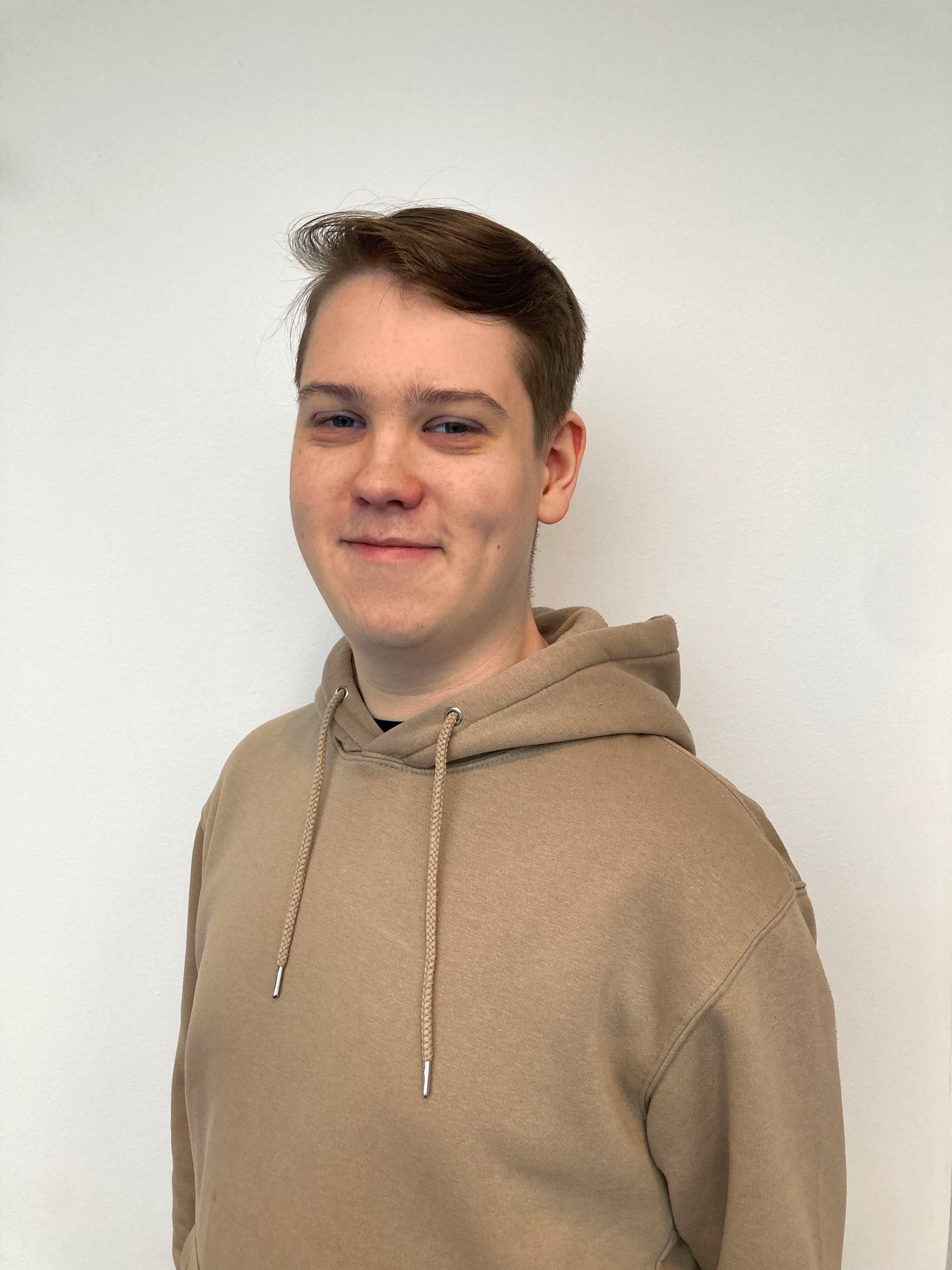 Portrait of a young man wearing a student cap and a black suit with a red tie.